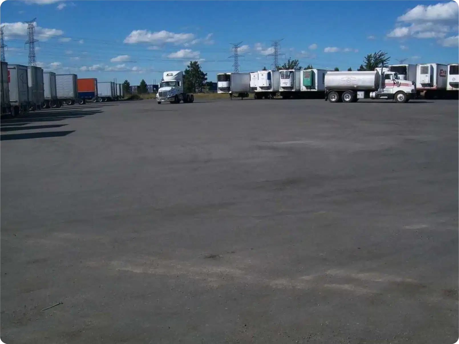 Trucks and trailers parked on a lot for recycled asphalt rejuvenation equipment and transport.