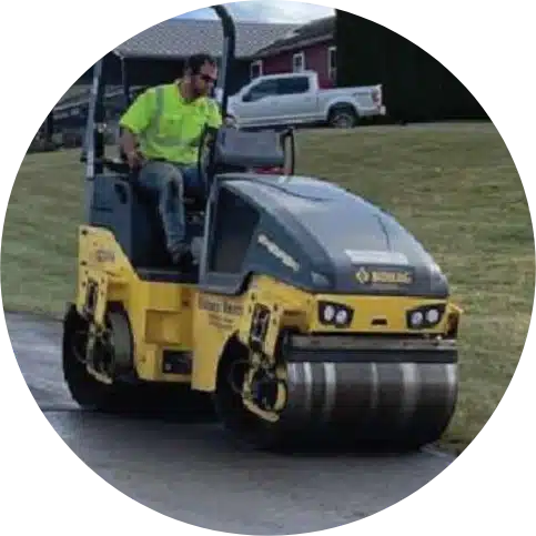 Man driving yellow steamroller on a paved surface with recycled asphalt rejuvenation process.