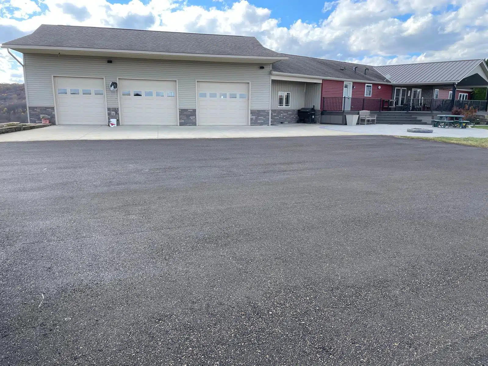_Image_ (21) House with three garage doors and a fresh asphalt driveway beneath a partly cloudy sky.