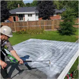 innovation 2 Person using hose to apply Reactiv8 white roof coating in backyard on sunny day.