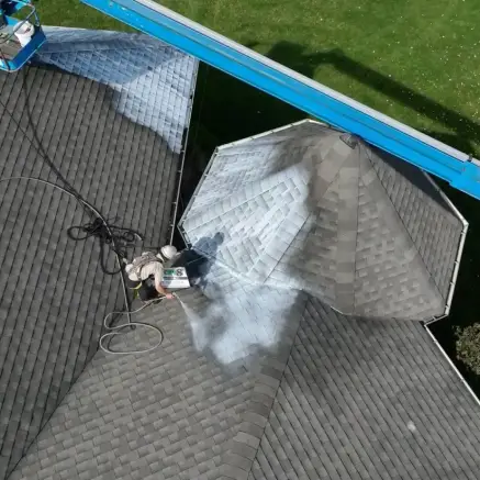 Worker on lift power washing gray shingled roof in DC Baltimore area for LP Dealers.