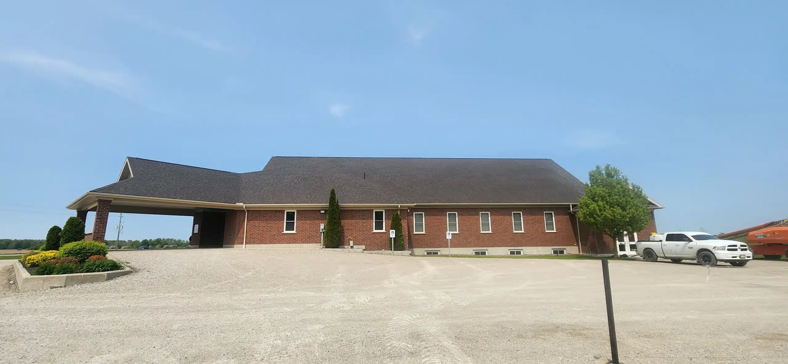Red brick Donegal, Ontario building with missing shingles and a white truck parked in front.