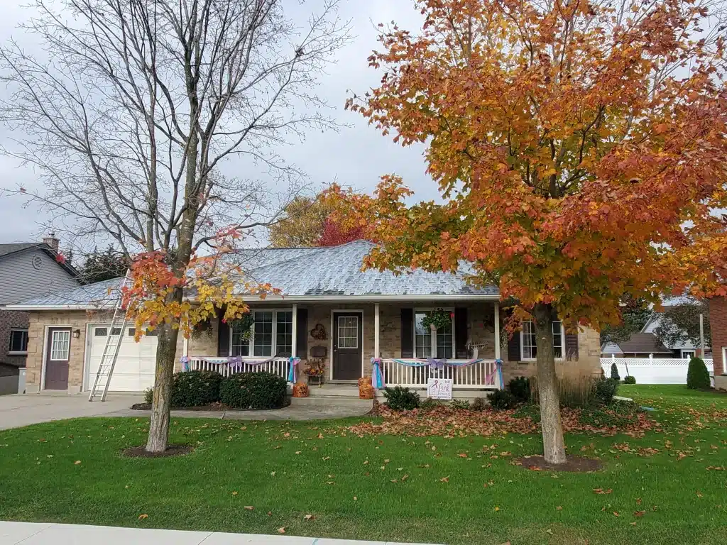 One-story brick bungalow with porch, autumn trees, and scattered leaves on the front lawn.