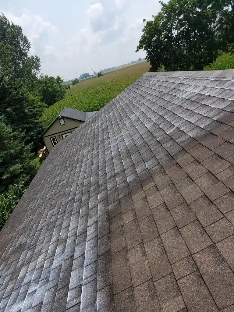 Asphalt shingle roof view in Palmerston Ontario with fields, trees, and a distant cottage.